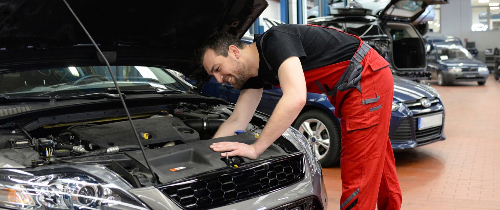 Meccanico al lavoro sul motore di un'auto nell'officina San Basilio